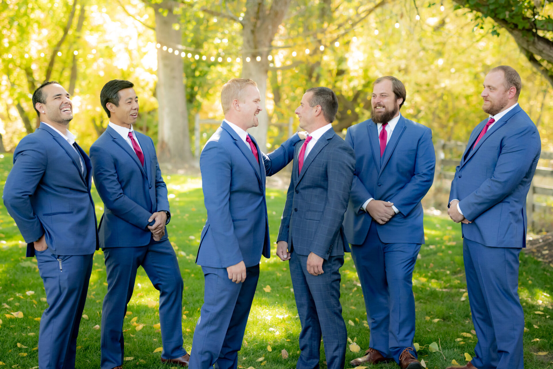 Groom in a navy-blue suit talking to his groomsmen who are dressed in light blue suits