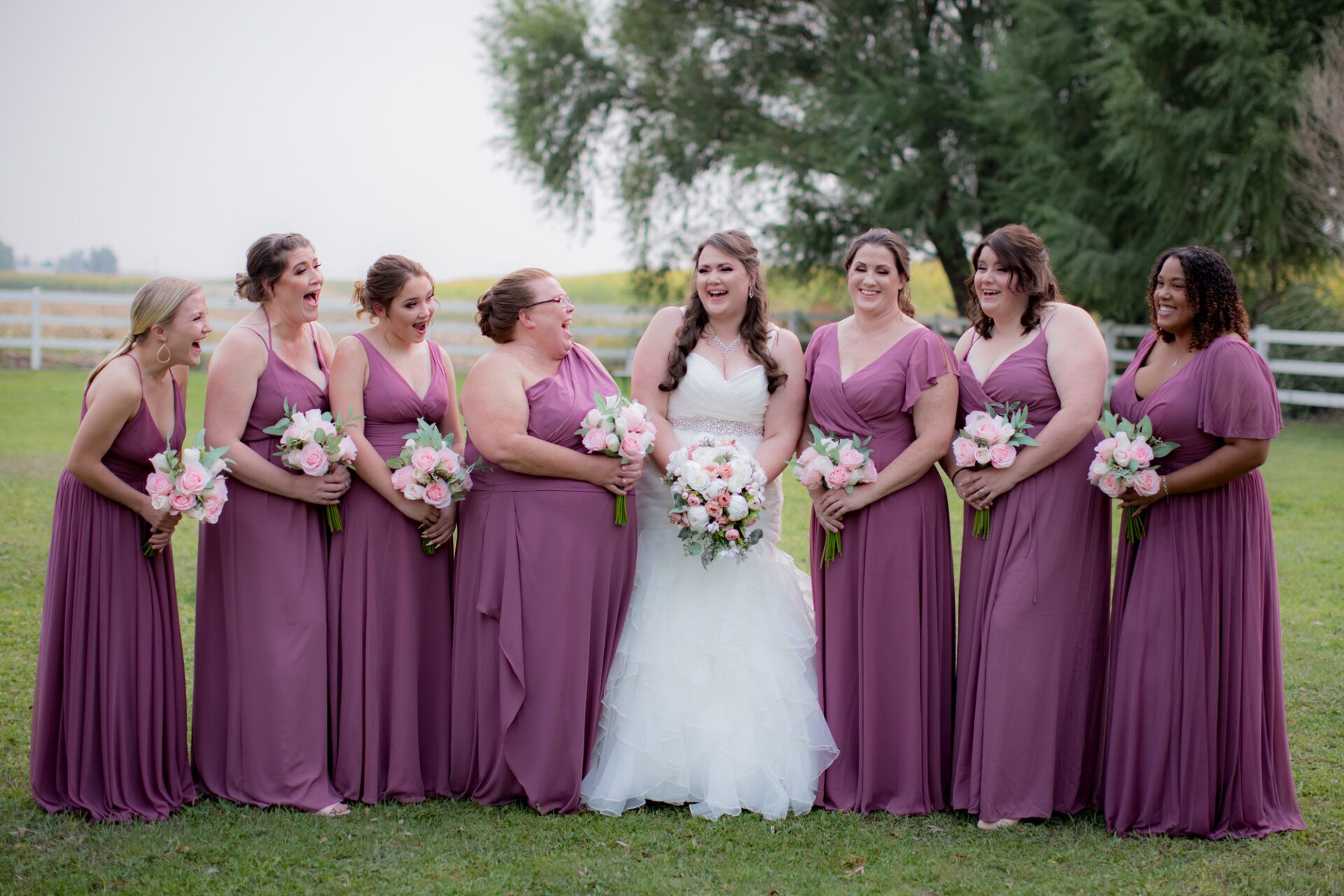Happy bride in between her bridesmaid who are wearing lavender dresses
