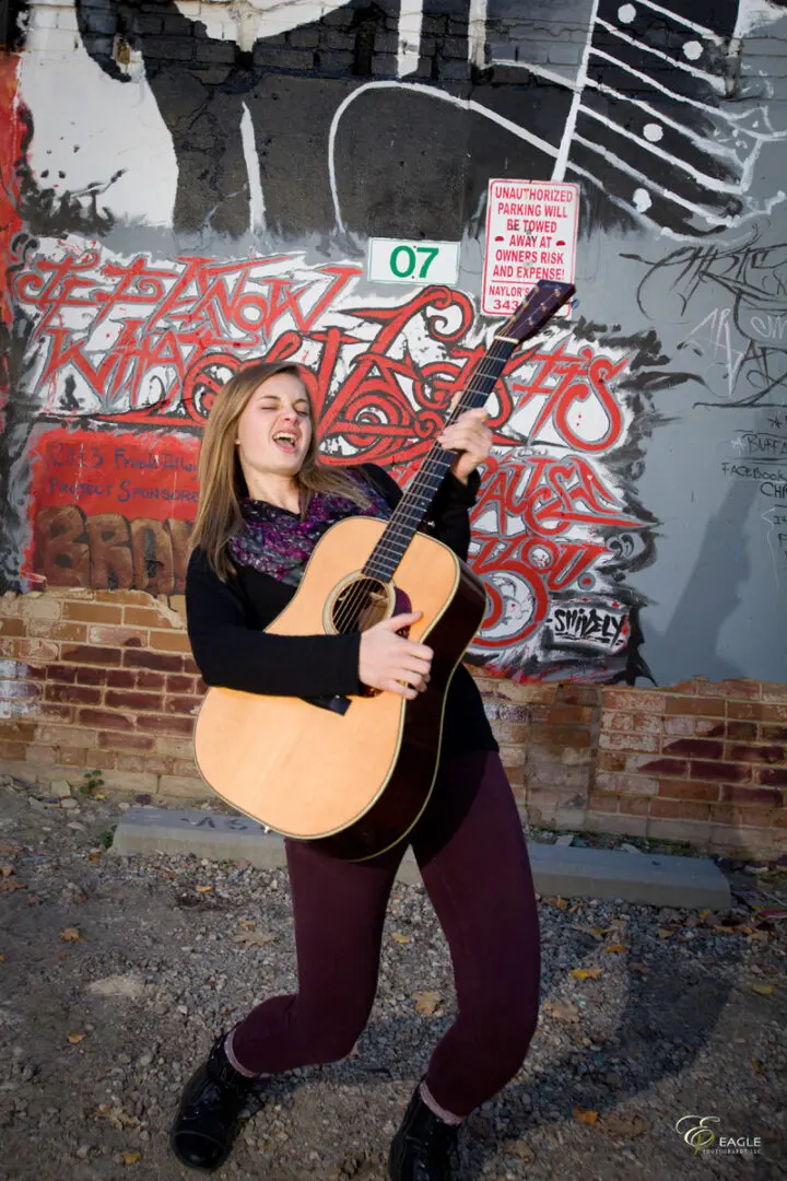 A young woman rocking out with her acoustic guitar