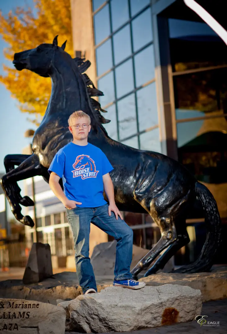 A young man posing next to a horse statue
