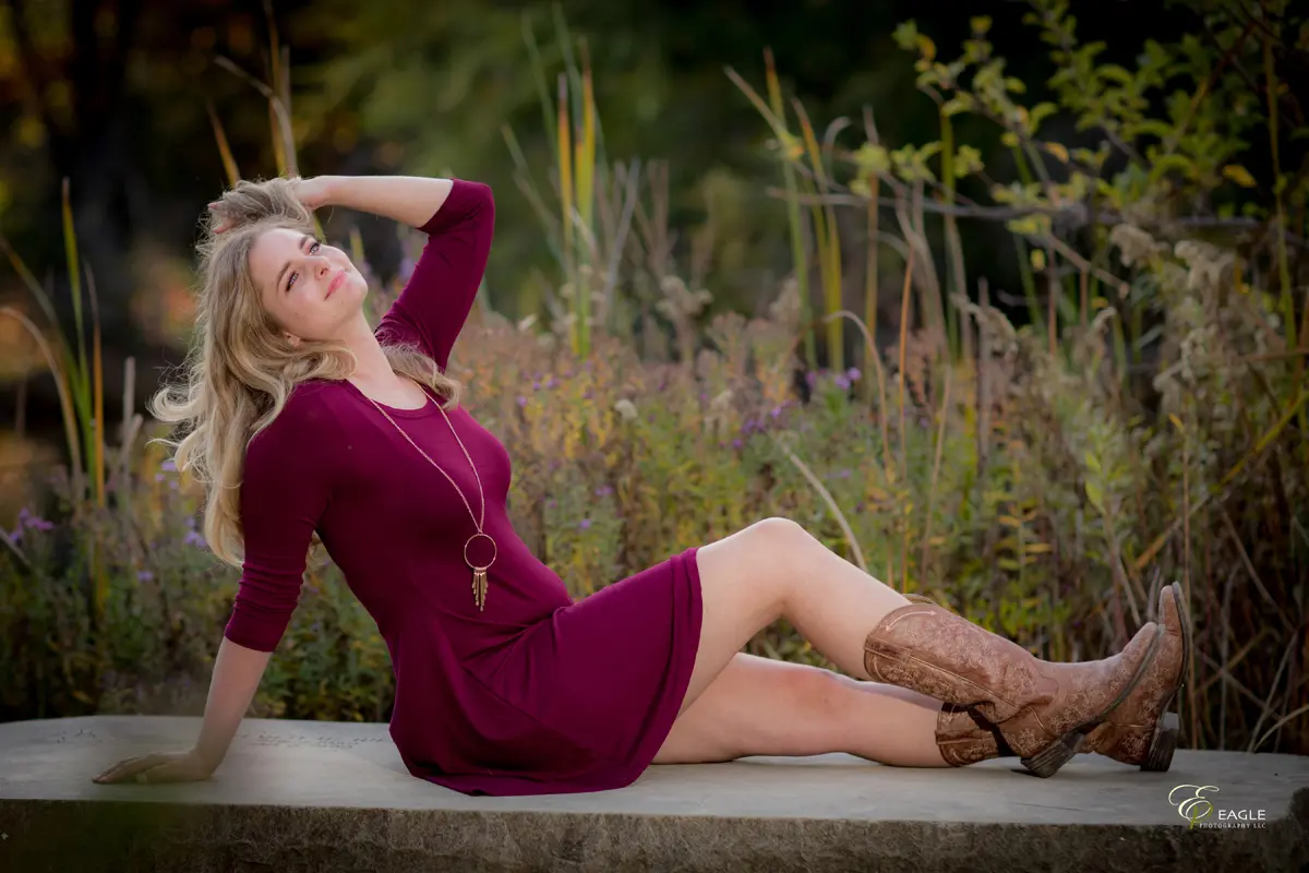 A woman wearing a wine-colored dress and cowboy boots