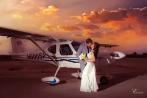 A married couple kissing in front of a plane