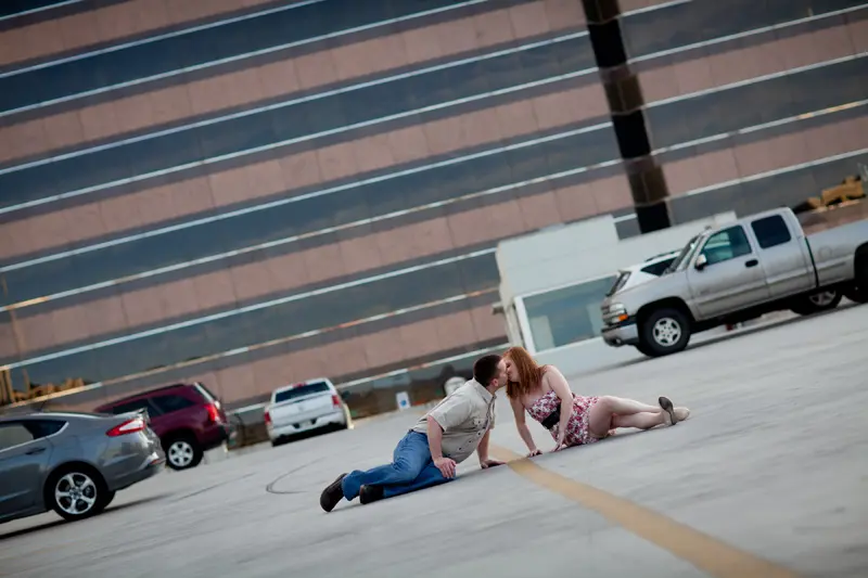A couple sitting and kissing in a parking lot